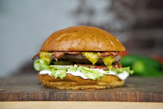 Булочка Бриошь, соус сливочный, салат Айсберг, помидор, котлета из говядины, медово-горчичный соус, жаренный бекон.