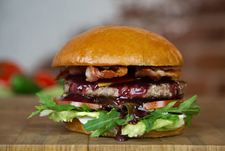 Булочка Бриошь, соус сливочный, салат Айсберг, помидор, маринованный огурчик, котлета из говядины,  двойной Чеддар, соус чёрный Перечный, соус Винно-брусничный, бекон.