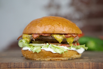 Булочка Бриошь, соус сливочный, салат Айсберг, помидор, маринованный огурец, котлета из говядины, медово-горчичный соус, жаренный бекон.